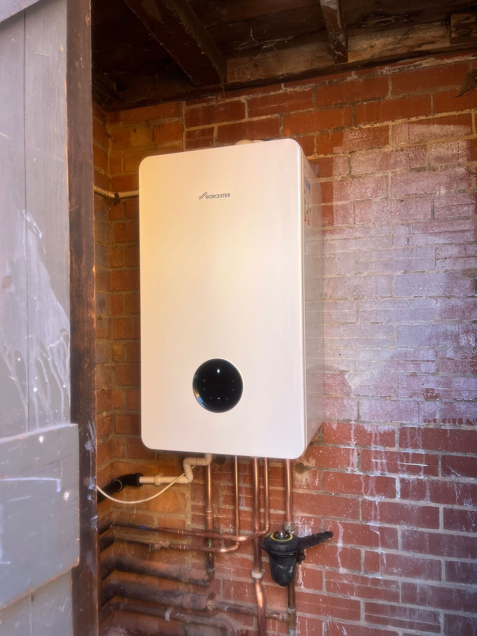 Worcester combi boiler installed on a brick wall in an outbuilding