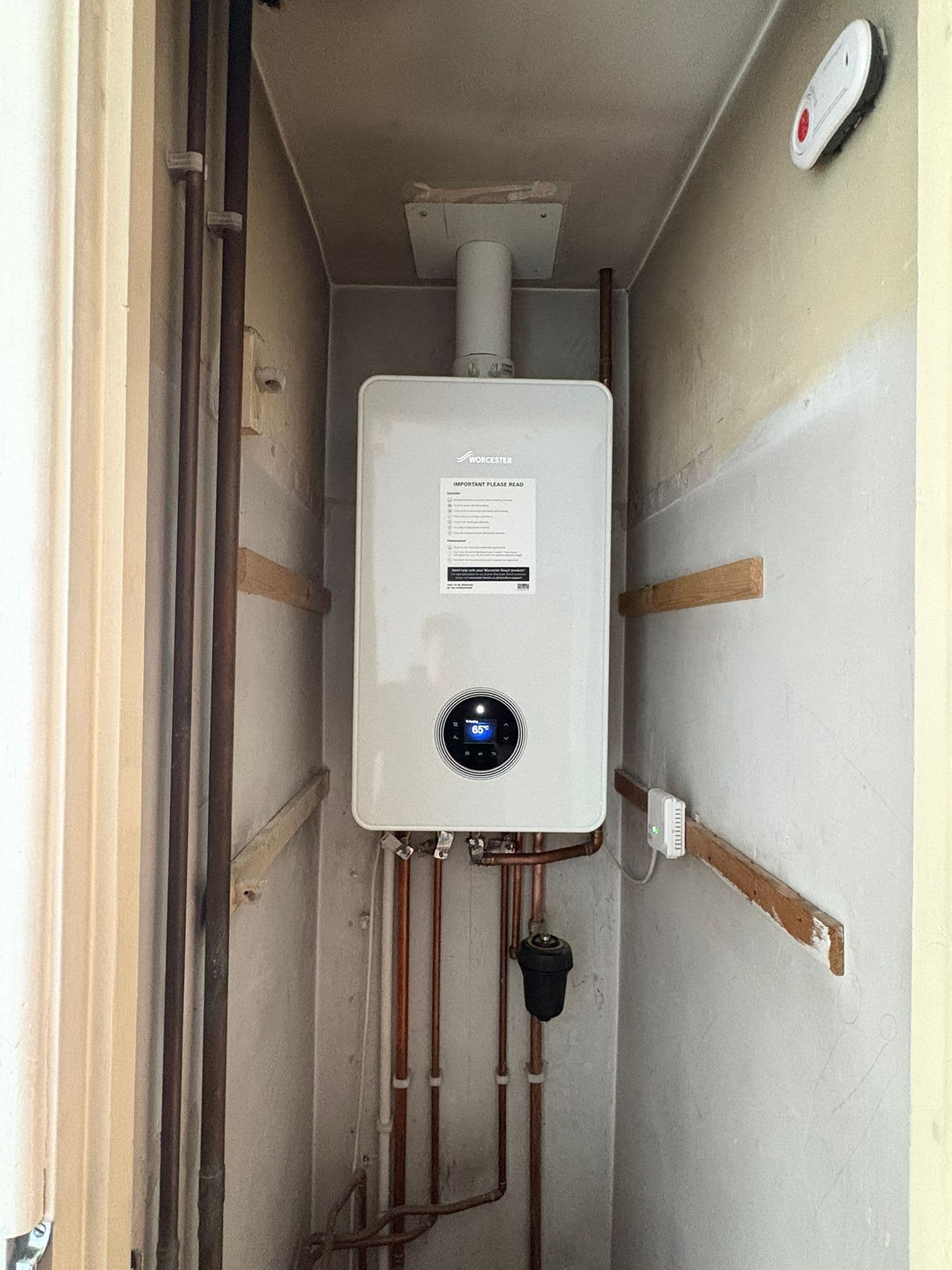 Worcester combi boiler fitted into a tight stair recess with neat pipework