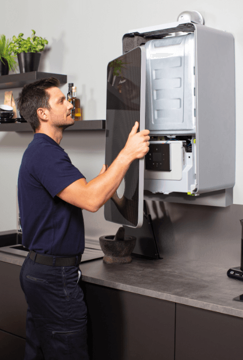 HeatNI engineer servicing a wall-mounted combi boiler in a homeowner's kitchen